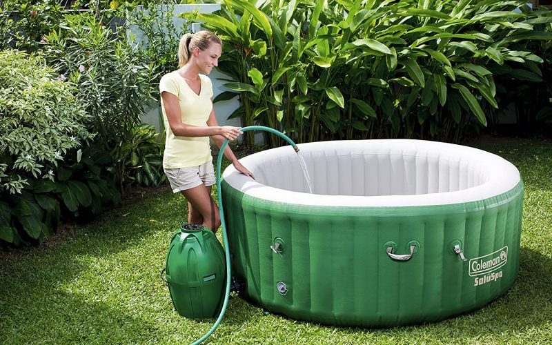 White-Haired woman filling Coleman SaluSpa Inflatable Hot Tub with a hose
